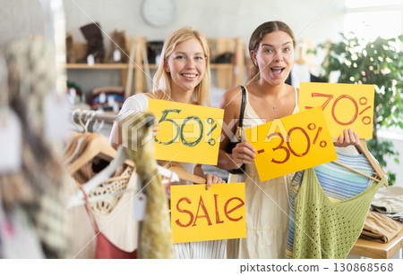 Two women with discount posters in the store Two women with discount posters in the store 130868568