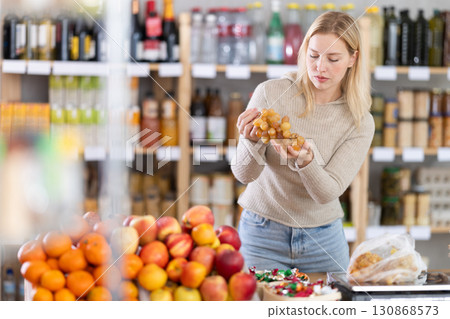 Young woman choosing grapes in grocery store Young woman choosing grapes in grocery store 130868573