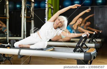 Elderly woman doing side bends 130868587