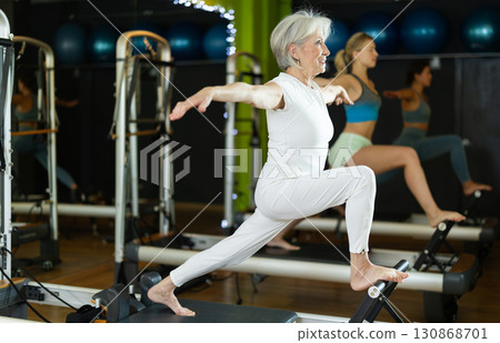 Mature woman actively doing Pilates exercises Mature woman actively doing Pilates exercises 130868701