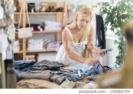 Young female customer scans QR code on trousers or shorts label Young female customer scans QR code on trousers or shorts label 130868704