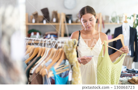 Young woman choosing stylish tank tops in a clothing store 130868723