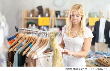 Young woman choosing lazy clothes at discounts 130868736