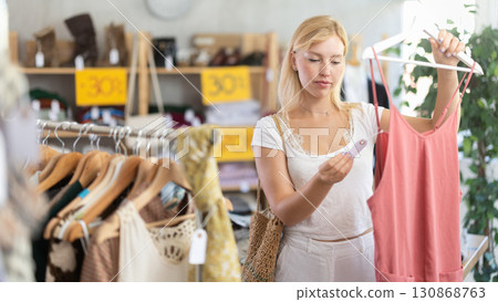 Fashionista girl near showcase examine goods, buying something clothing for summer. 130868763