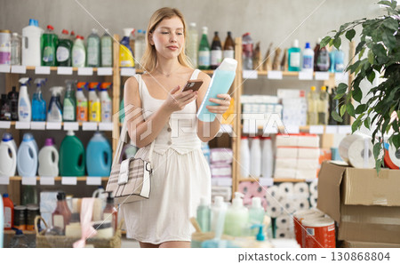 Young woman in summer clothes scanning QR-code on shampoo in store Young woman in summer clothes scanning QR-code on shampoo in store 130868804