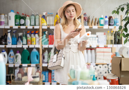 Young woman scanning bottle of sunscreen in personal care store Young woman scanning bottle of sunscreen in personal care store 130868826