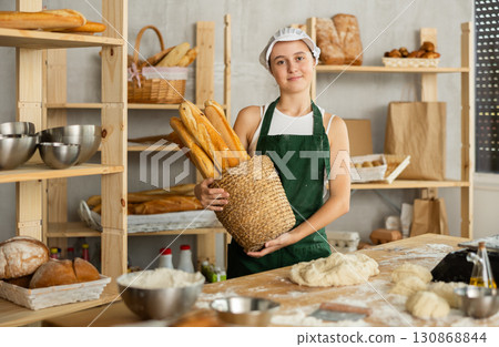 Teenage girl with basket of baguettes in bakery 130868844