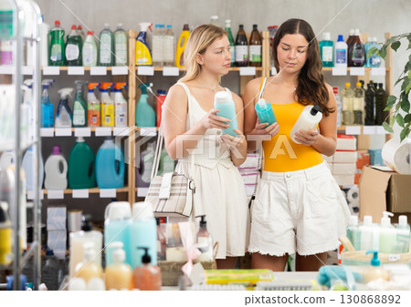 Young girls in summer clothes choosing shampoo in store Young girls in summer clothes choosing shampoo in store 130868892