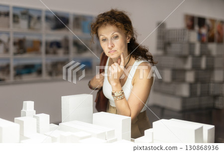 Middle-aged woman looking at building models in museum 130868936