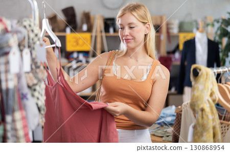 Young woman choosing jumpsuit in clothing store 130868954