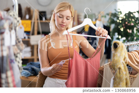 Young woman choosing jumpsuit in clothing store Young woman choosing jumpsuit in clothing store 130868956