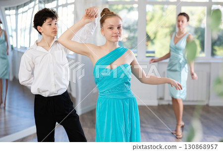 Couple of teenagers in evening dresses are learning to dance an polonaise dance 130868957