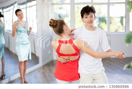 Teenage boy and girl performing waltz in pair during dance lesson 130868986