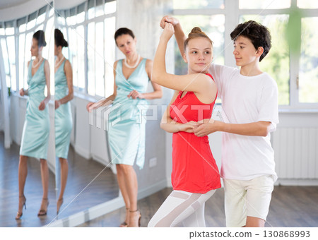 Motivated adolescent ballroom dancers practicing dance moves in studio Motivated adolescent ballroom dancers practicing dance moves in studio 130868993