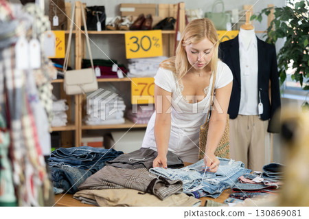 Fashionista girl near showcase examine goods, buying shorts or trousers 130869081