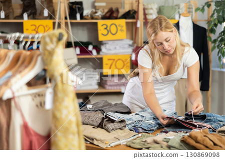 Fashionista girl near showcase examine goods, buying shorts or trousers 130869098