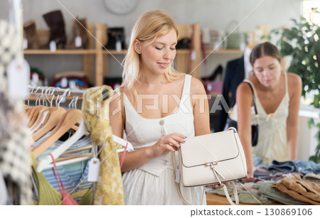 Young girl near showcase examine goods, buying handbag. Client looking for something in background 130869106
