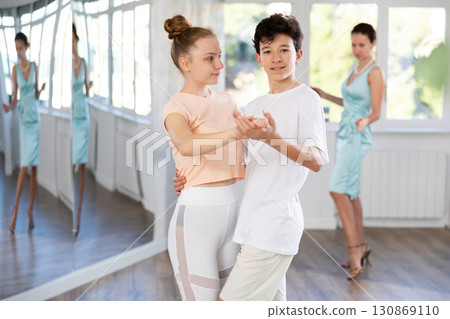 Couple of teenage dancers rehearsing ballroom dance with female teacher Couple of teenage dancers rehearsing ballroom dance with female teacher 130869110