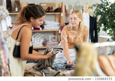 Two young women choosing trousers in store 130869155