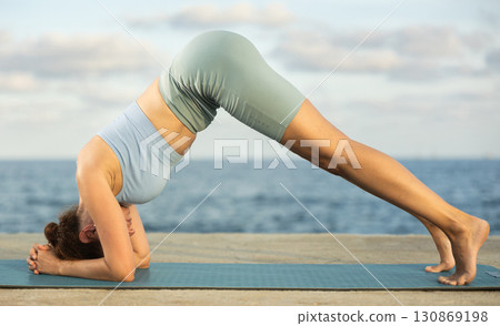 Yoga practice on embankment, female athlete fulfil carry out Ardha Shirshasana Yoga practice on embankment, female athlete fulfil carry out Ardha Shirshasana 130869198