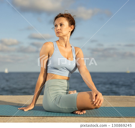 Woman performing Ardha Matsyendrasana position yoga training Woman performing Ardha Matsyendrasana position yoga training 130869245