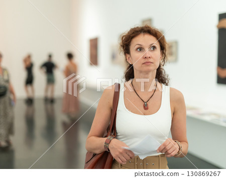 Woman captivated by abstract paintings at art museum 130869267