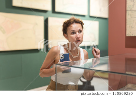 Woman observing artifacts inside glass display case at museum Woman observing artifacts inside glass display case at museum 130869280