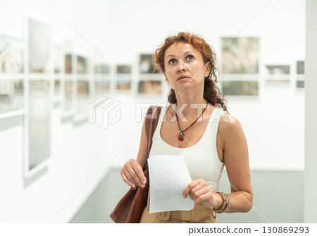 Woman observing photographs on display in photo gallery 130869293