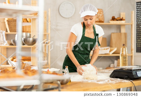 Woman baker kneading dough Woman baker kneading dough 130869348