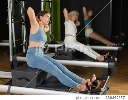 Woman in sportswear sitting on reformer platform 130869357