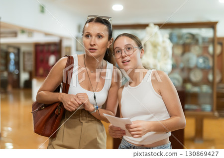 Young woman with teen daughter walk around museum, cookware zone. 130869427