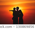 (AI-generated) Family image: Silhouette of a young parent and child standing together in the sunset 130869856