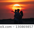 (AI-generated) Family image: A large sunset and the silhouette of a parent and child standing together 130869857