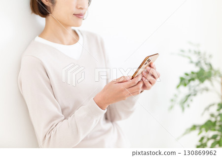 一位隨興的中年女商務女士正在看她的智慧型手機 一位隨興的中年女商務女士正在看她的智慧型手機 130869962