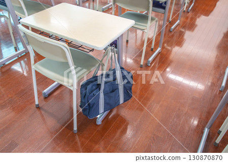Close-up of desks and chairs in a classroom with school bags hanging from the back, school image Close-up of desks and chairs in a classroom with school bags hanging from the back, school image 130870870