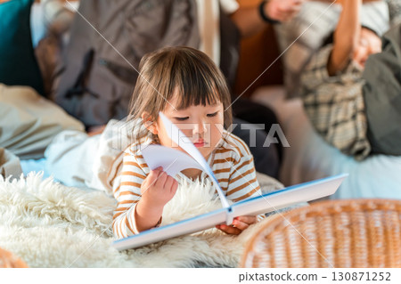 Child, girl reading a picture book on the bed Child, girl reading a picture book on the bed 130871252
