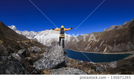 Backpacking woman hiking on high altitude mountain top 130871265