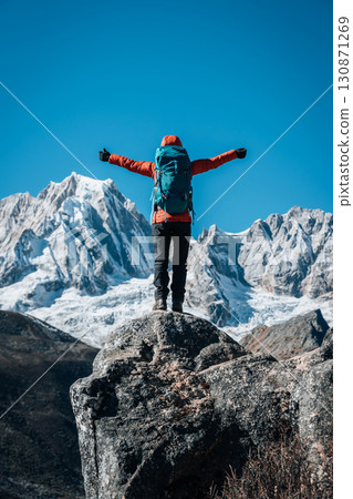 Backpacking woman hiking on high altitude mountain top 130871269