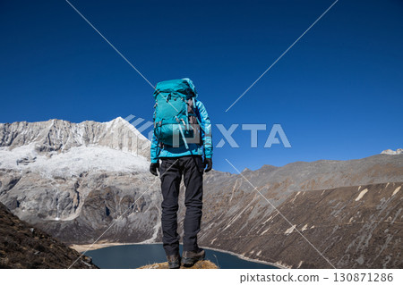 Backpacking woman hiking on high altitude mountain top 130871286