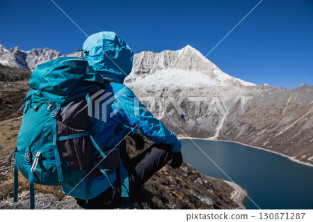 Backpacking woman hiking on high altitude mountain top 130871287