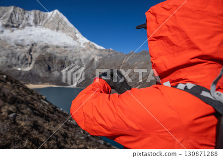 Backpacking woman set the sports watch on high altitude mountain top Backpacking woman set the sports watch on high altitude mountain top 130871288