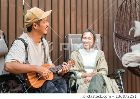 一對夫婦坐在躺椅上彈奏尤克里裡放鬆身心 一對夫婦坐在躺椅上彈奏尤克里裡放鬆身心 130872251