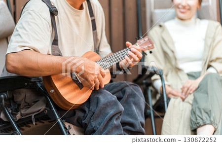一對夫婦坐在躺椅上彈奏尤克里裡放鬆身心 一對夫婦坐在躺椅上彈奏尤克里裡放鬆身心 130872252