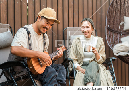 A couple relaxing while playing the ukulele and sitting in a reclining chair A couple relaxing while playing the ukulele and sitting in a reclining chair 130872254