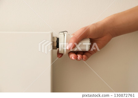 Someone adjusts a radiator valve for heat control Someone adjusts a radiator valve for heat control 130872761