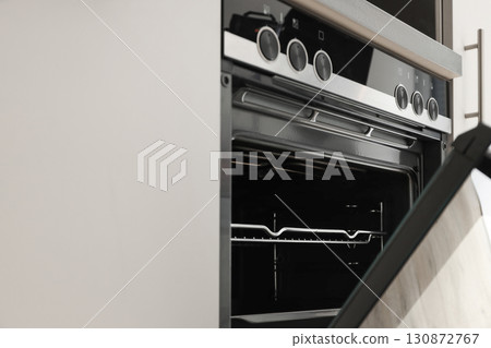 Modern oven with an open door showing racks and controls Modern oven with an open door showing racks and controls 130872767