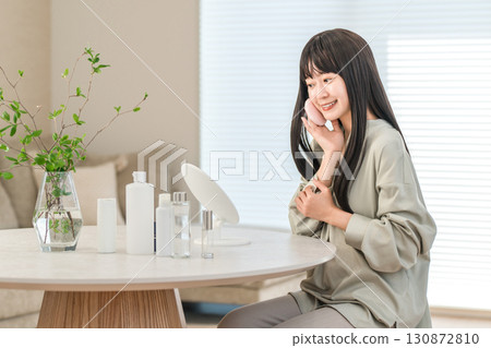 Smiling Asian woman applying foundation, powder, and makeup Smiling Asian woman applying foundation, powder, and makeup 130872810