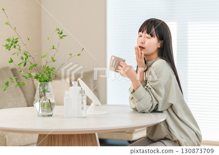 A woman yawning in the morning after waking up and drinking coffee or hot water (lack of sleep, lack of sleep) 130873709