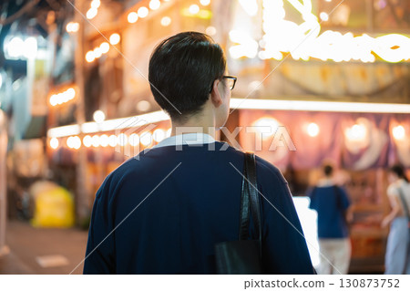 Rear view of a man walking through a bar district at night Rear view of a man walking through a bar district at night 130873752