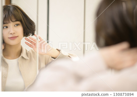 Mirror portrait of woman applying makeup Mirror portrait of woman applying makeup 130873894